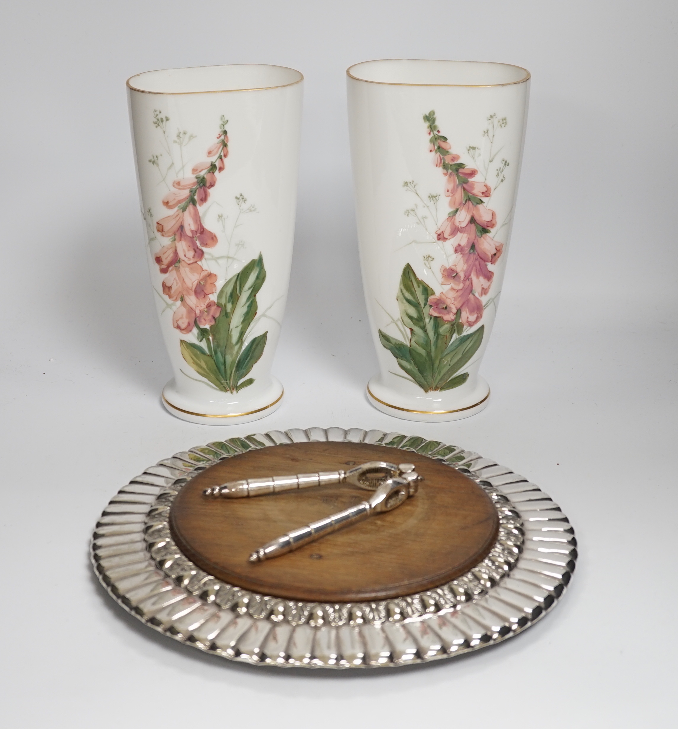 A pair of French opaque white glass vases enamelled with foxgloves, a plated bread board and a plated nutcracker, vases 25cm high